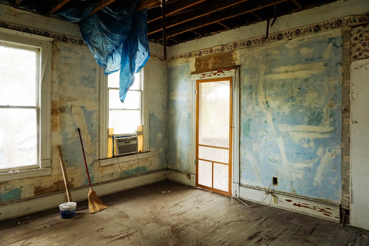 why-choose-us An empty room in an abandoned house with peeling walls and construction tools.