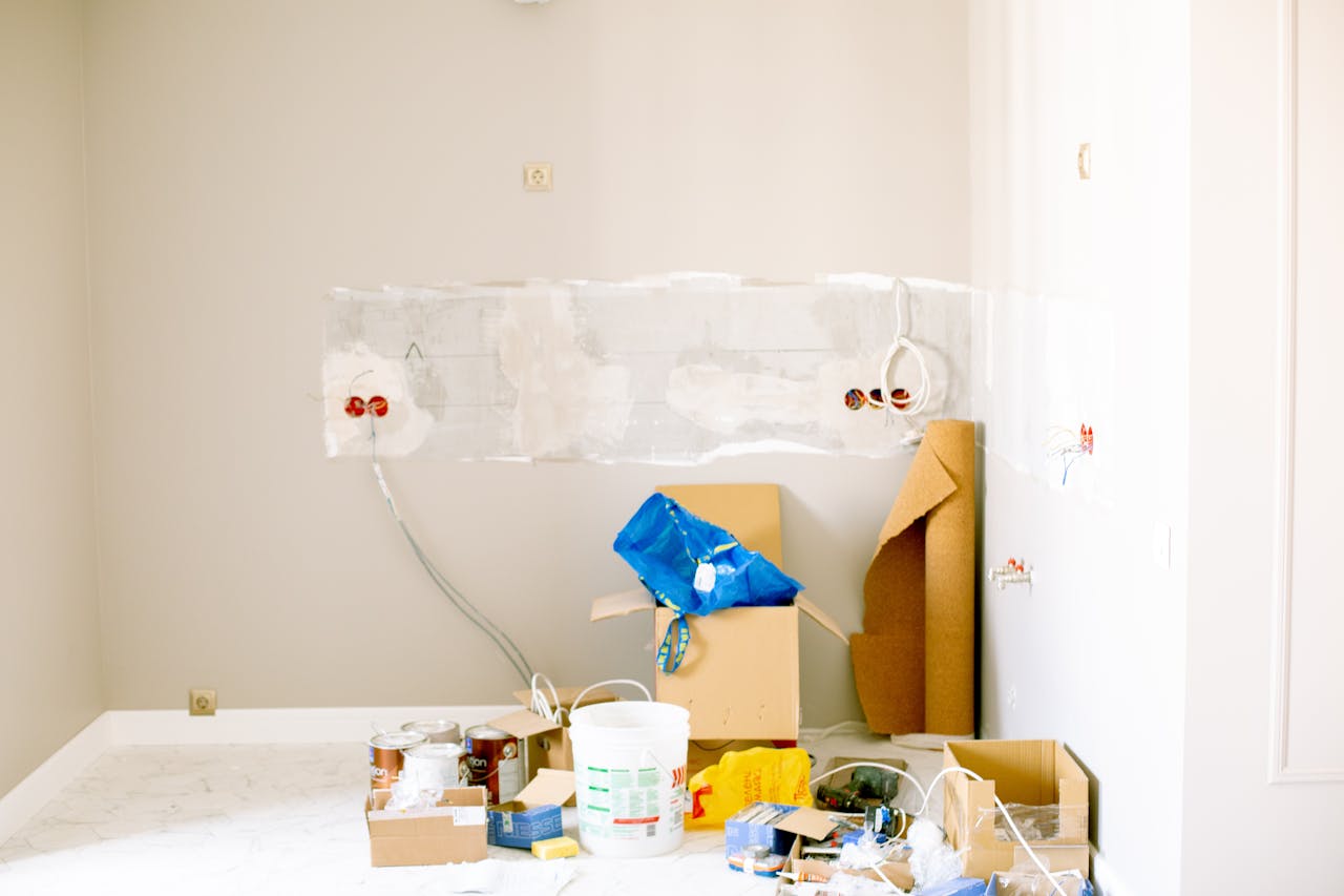 our-services-1 A room undergoing renovation with tools, supplies, wiring, and paint cans scattered around.