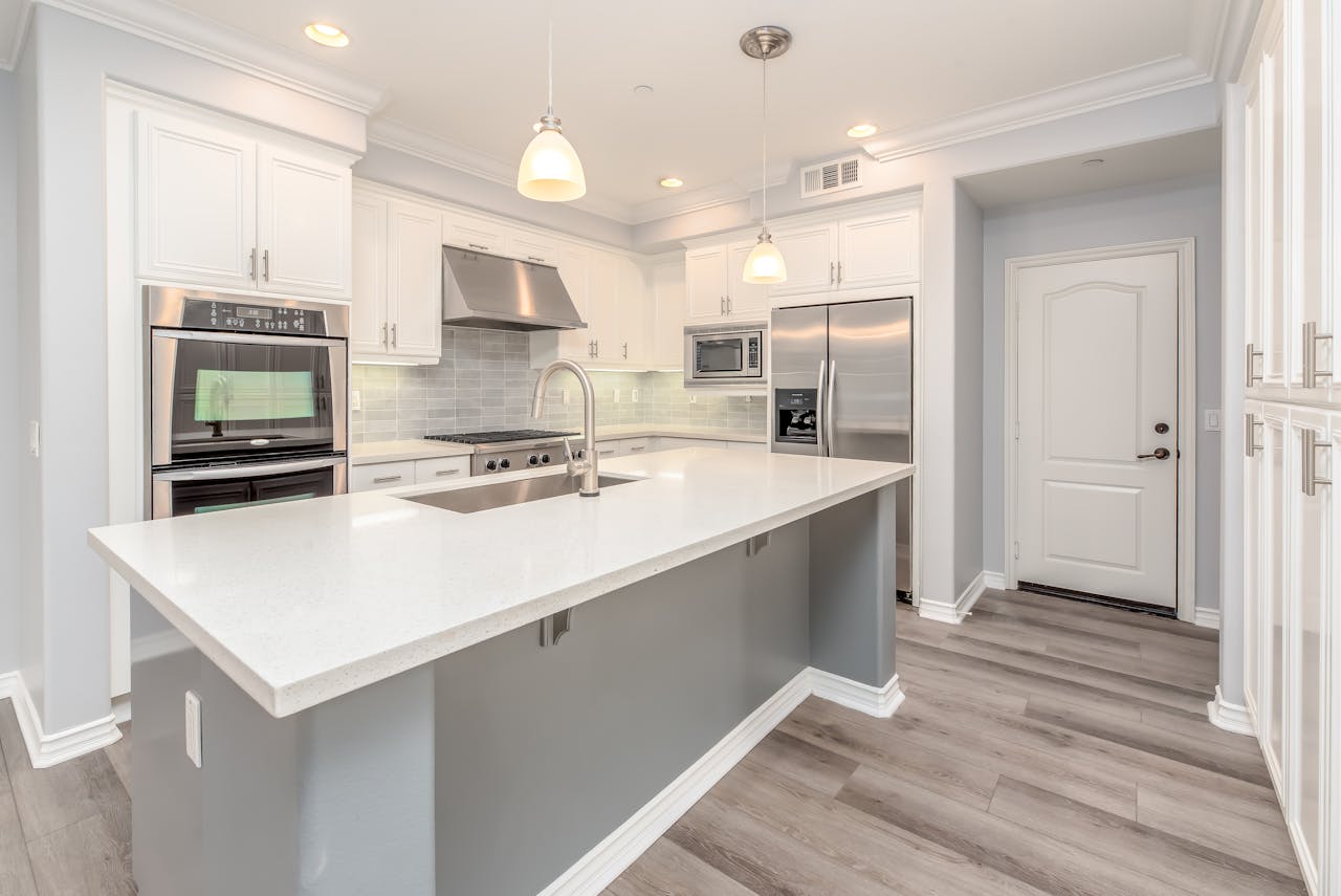 services-01 Modern kitchen interior featuring sleek white cabinetry and stainless steel appliances.