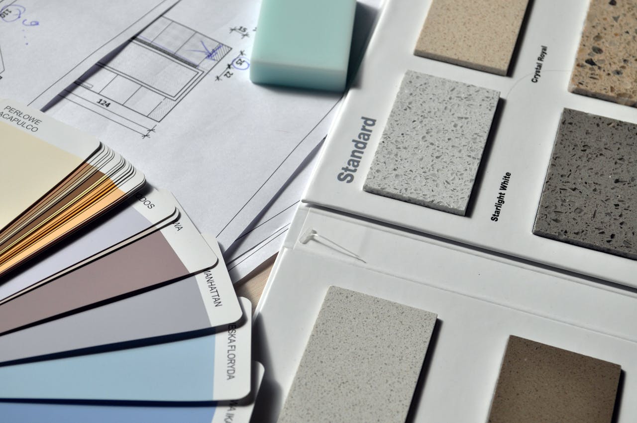 hero-img-01 Color palette and material samples for interior renovation projects on a blueprint.